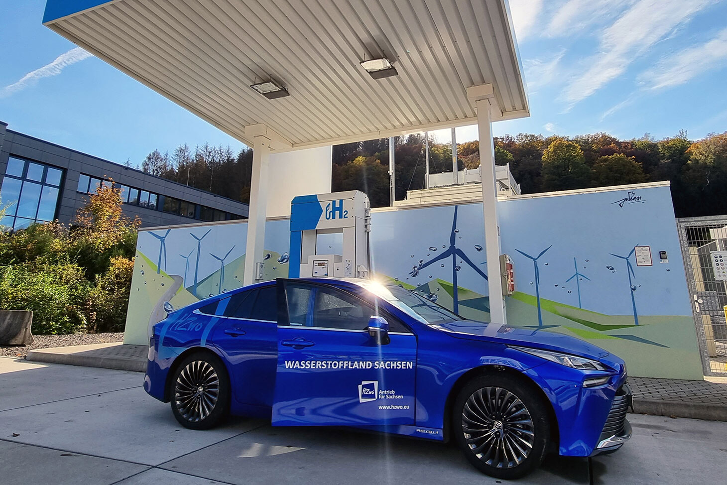 Ein blauer PKW steht an einer Wasserstoff-Tankstelle.