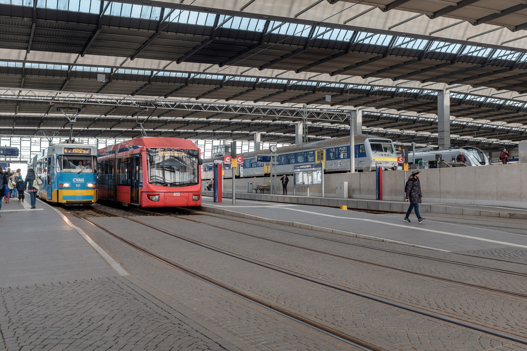 Blick in den Hauptbahnhof Chemnitz mit Straßenbahn, Bus und Zügen im Hintergund.
